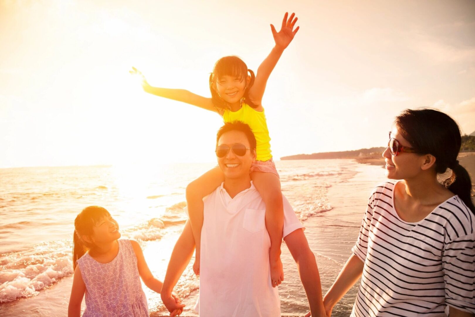 A family is standing on the beach at sunset.